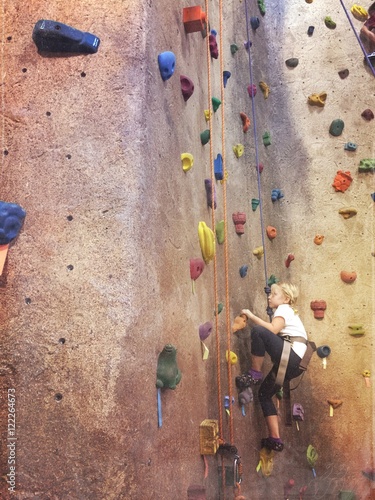 young girl rock climbing on wall
