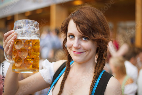 Portrait of cheerful young woman wearing traditional dirndl and holding a 1 liter beer stein at Oktoberfest