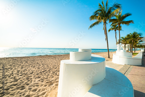 Deserted Fort Lauderdale South Florida beach with iconic spiral wall and palm trees under brilliant blue sky