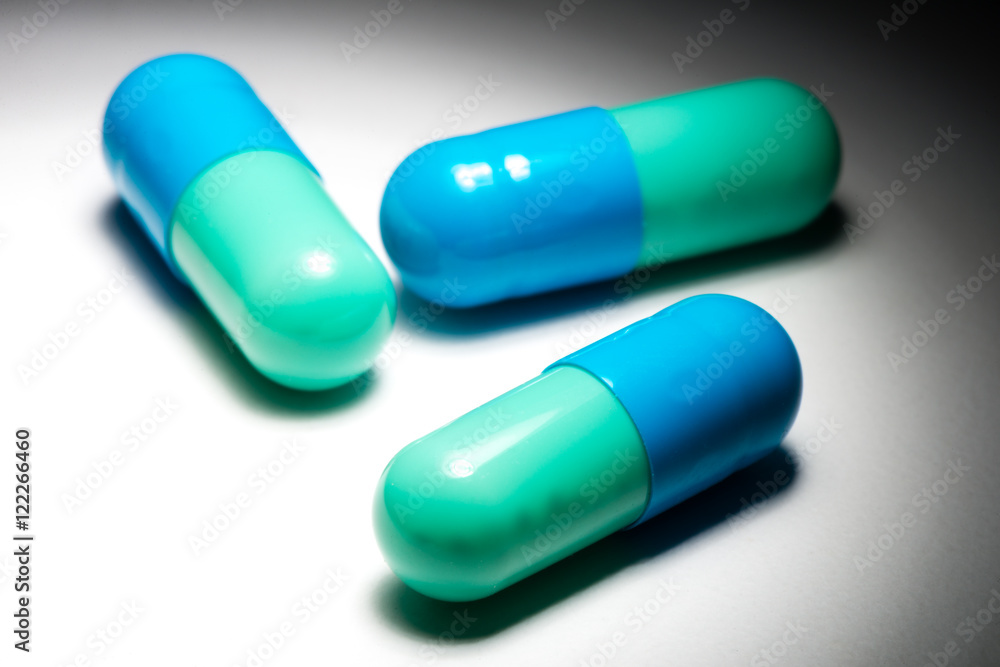 Blue green capsule pill medication on white