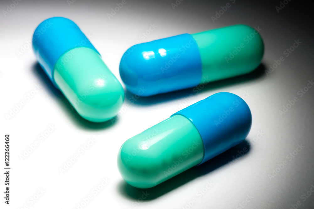 Blue green capsule pill medication on white Blue green capsule pill medication on white