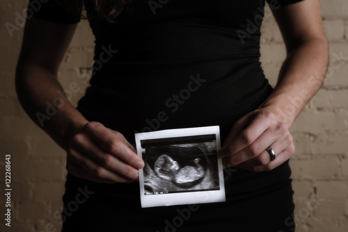Pregnant women holds sonogram of baby photo