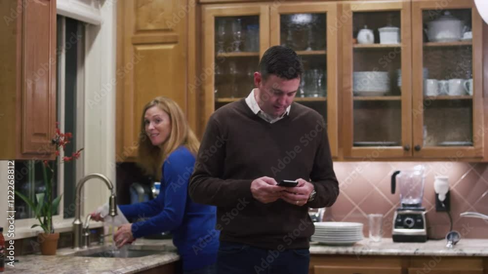 Husband and wife in the kitchen preparing dinner, both look at the camera Husband and wife in the kitchen preparing dinner, both look at the camera