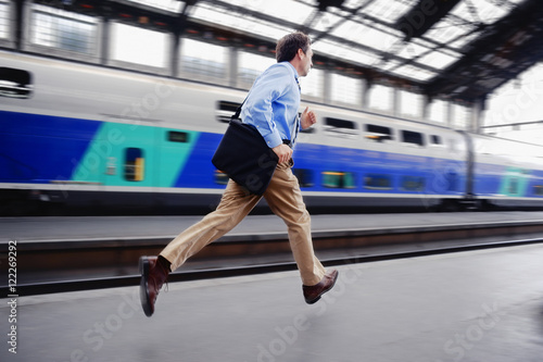 Rushed businessman running through railway station to catch last train