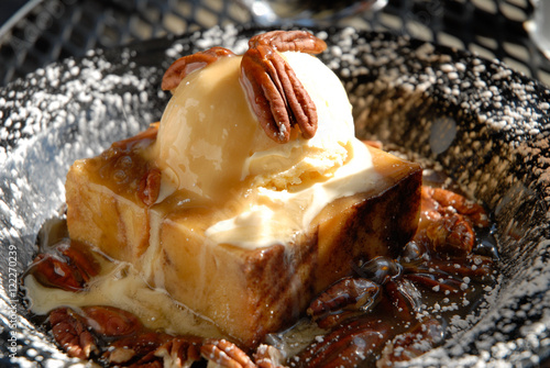 Bread pudding dessert topped with vanilla ice cream a la mode pecans and powdered sugar photo