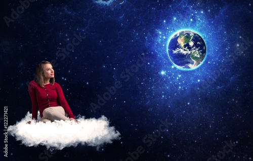 Woman sitting on cloud looking at planet earth © ra2 studio