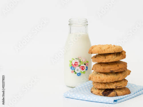 A snack time treat of homemade peanut butter and chocolate cookies and a small bottle of milk on a white, isolated background.