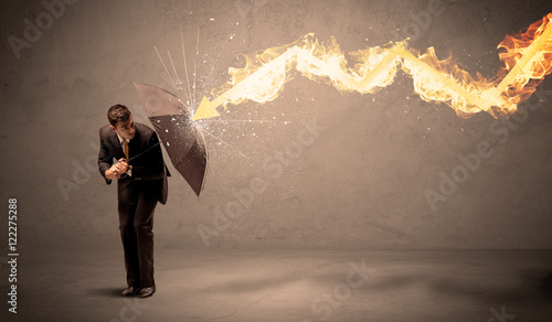 Business man defending himself from a fire arrow with an umbrell
