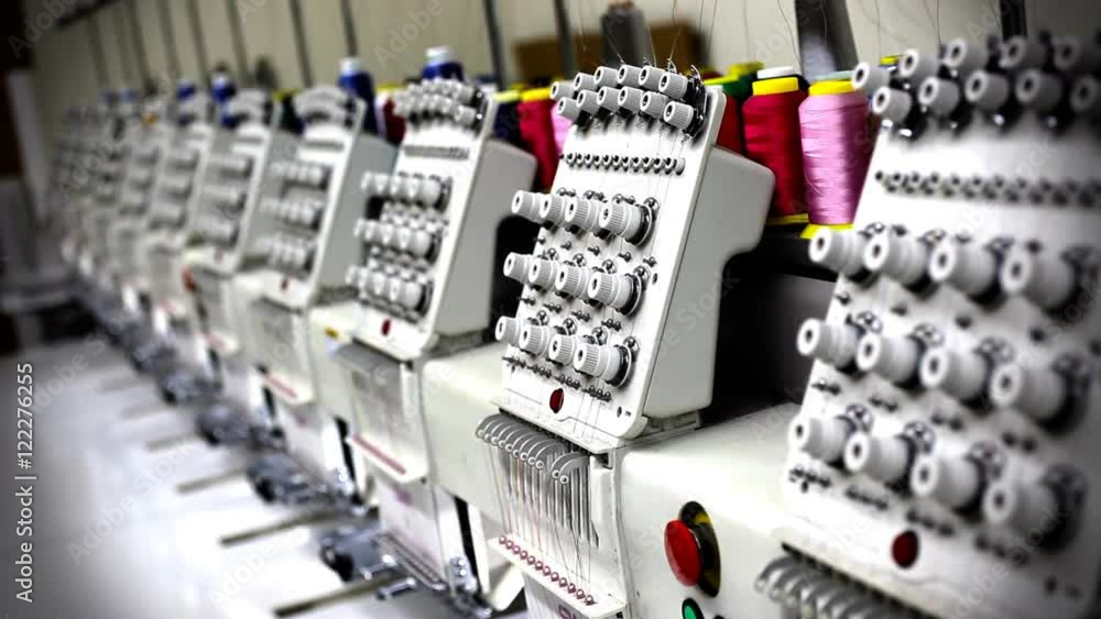 A row of industrial sewing machines used for manufacturing clothing. A row of industrial sewing machines used for manufacturing clothing.