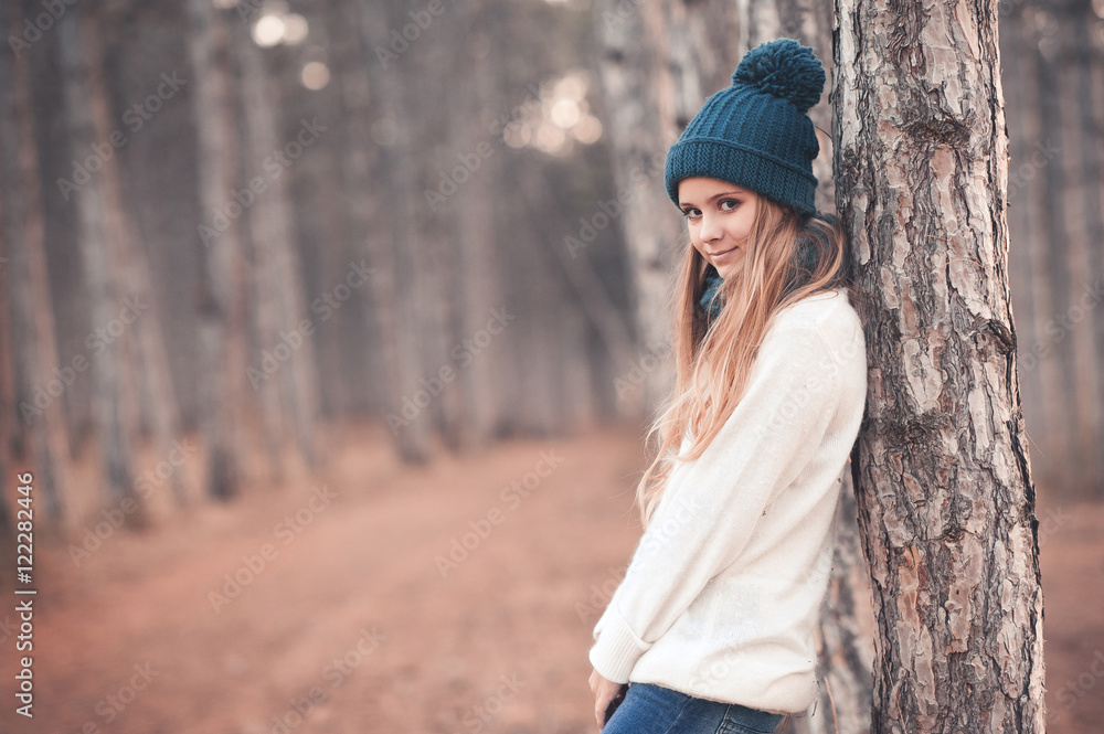 Stylish teen girl 14-16 year old wearing white knitted sweater and blue knitted hat posing in forest outdoors. Looking at camera. Winter season. Stylish teen girl 14-16 year old wearing white knitted sweater and blue knitted hat posing in forest outdoors. Looking at camera. Winter season.