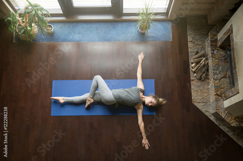Canvas Print Attractive young woman working out in living room, doing yoga exercise on wooden