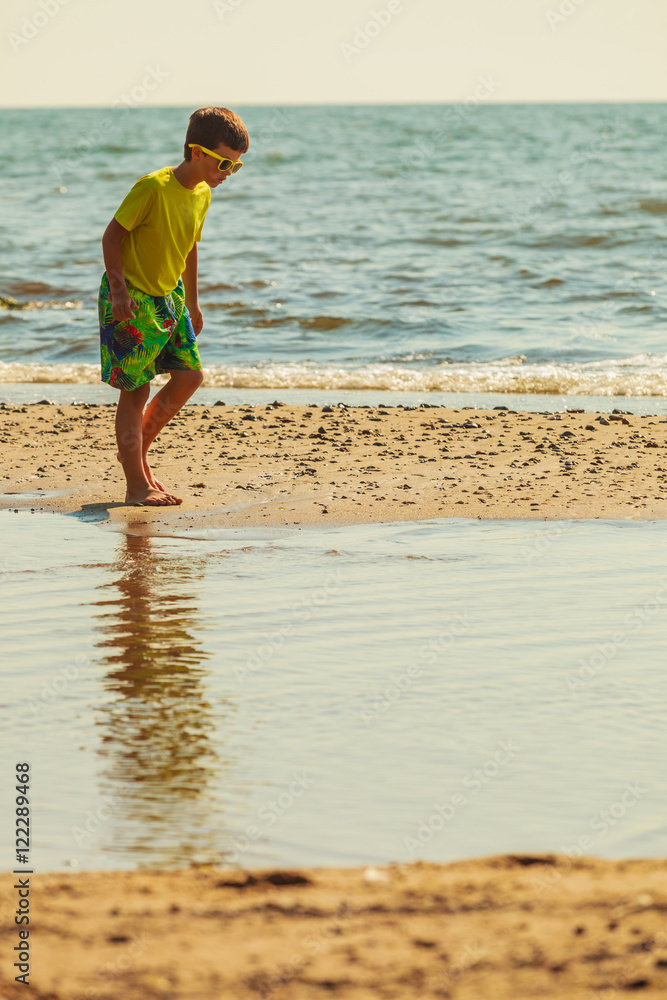 Boy walking on beach.