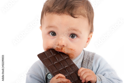 Adorable baby boy eating a plate of chocolate