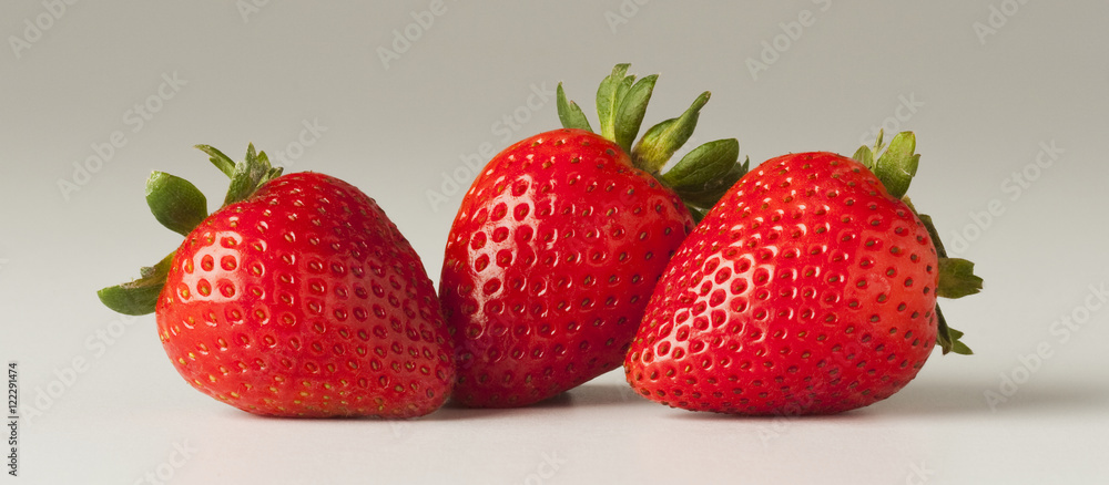 Agriculture - Three strawberries on a white surface. Agriculture - Three strawberries on a white surface.