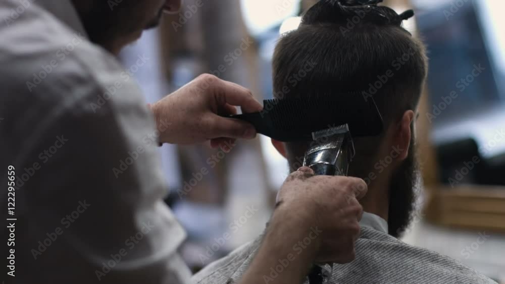 A British London barber using a scissors to cut a mans hair A British London barber using a scissors to cut a mans hair
