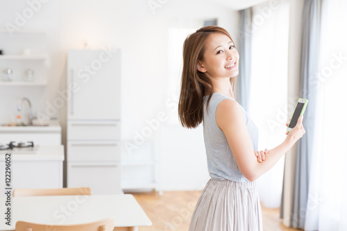 部屋でスマホを見る女性