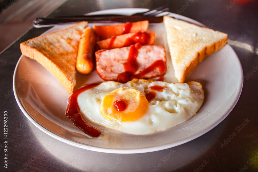 Breakfast with fried eggs, ham and sausages.