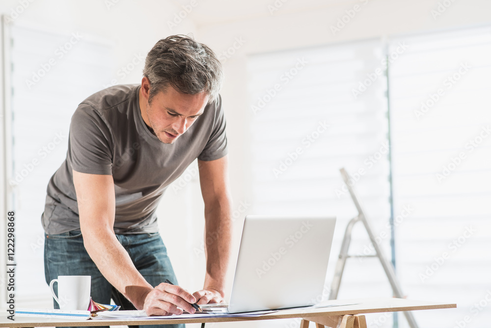 Craftsman using a computer to perform renovation work in a house