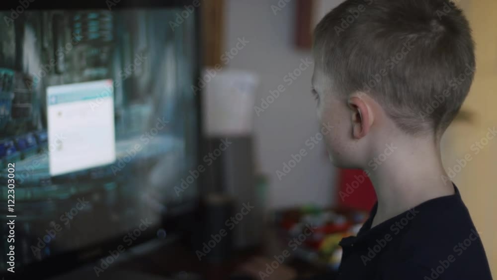 A little boy playing games on a computer in his room A little boy playing games on a computer in his room