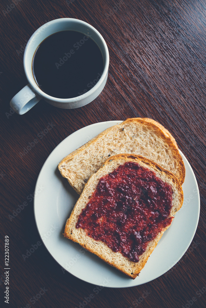 Bread with strawberry jam, and hot coffee on a wooden table. Pic Bread with strawberry jam, and hot coffee on a wooden table. Pic