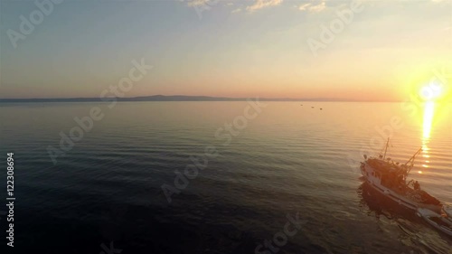 Commercial fishing boat on the calm sea at sunset aerial view