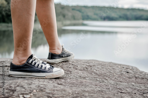 Feet women black sneakers  on nature. Selective focus and Hipster tone