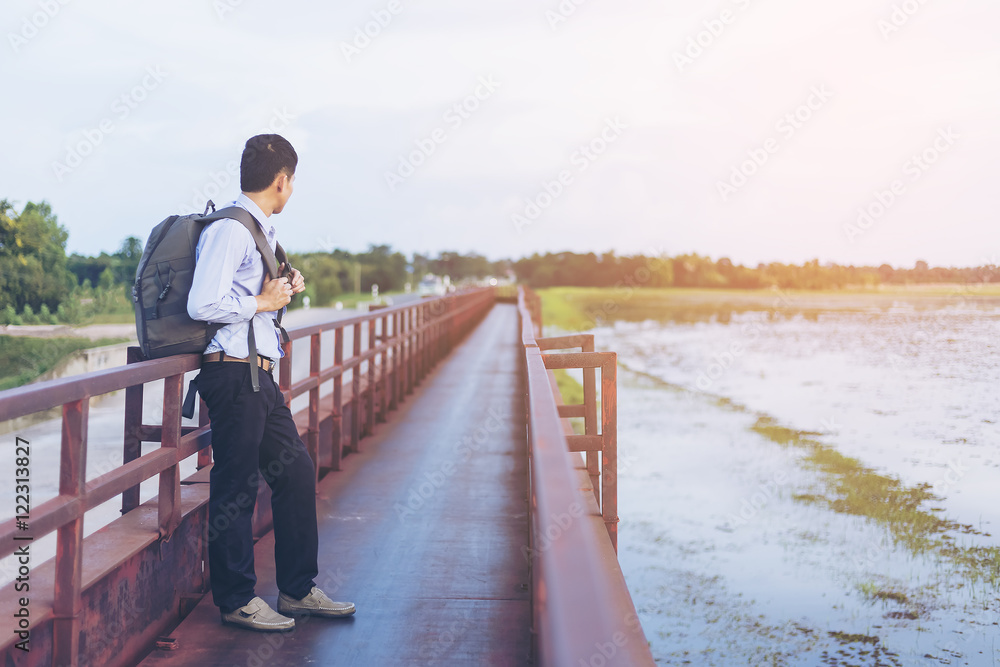 Tourist man with backpack standing on bridge and enjoying nature