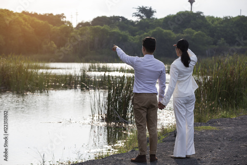 Rear view portrait of young man and woman standing on the waterf photo