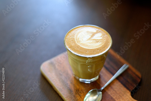 A cup of latte coffee on the wood plate and wood background