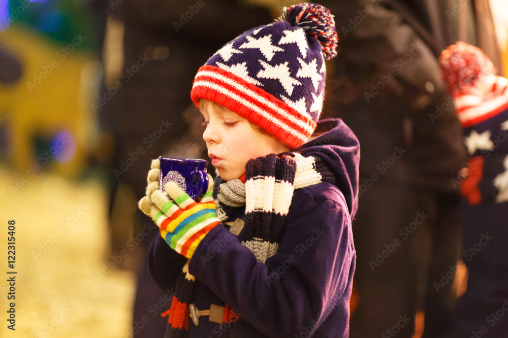 Little kid boy with hot chocolate on Christmas market