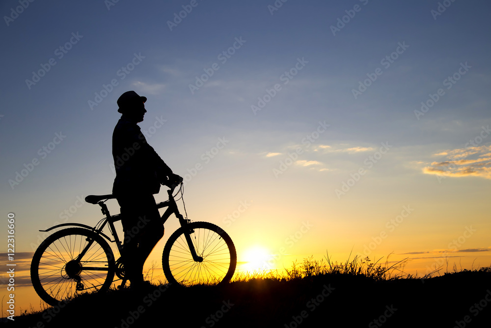 Silhouette of sports person cycling on the field on the beautifu Silhouette of sports person cycling on the field on the beautifu