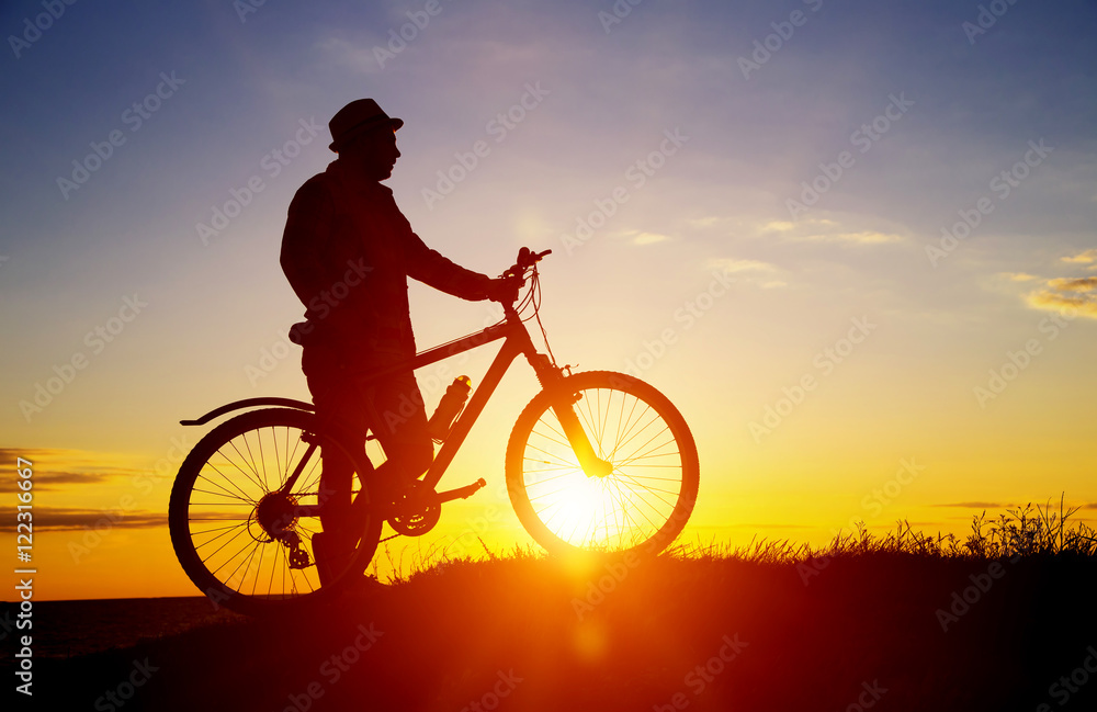 Silhouette of sports person cycling on the field on the beautifu
