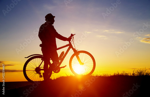 Silhouette of sports person cycling on the field on the beautifu © YURII Seleznov