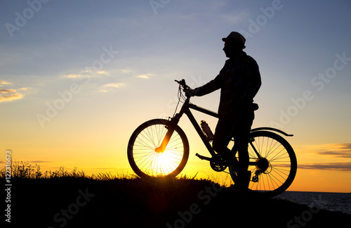 Silhouette of sports person cycling on the field on the beautifu