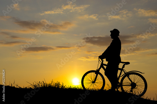 Silhouette of sports person cycling on the field on the beautiful sunset © YURII Seleznov