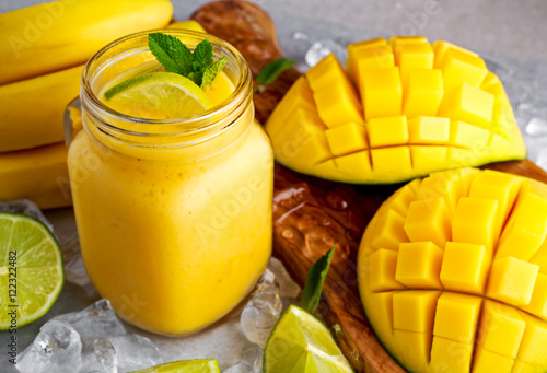 Healthy ripe Yellow Banana Mango Smoothie with slices of Lime, mint and ice