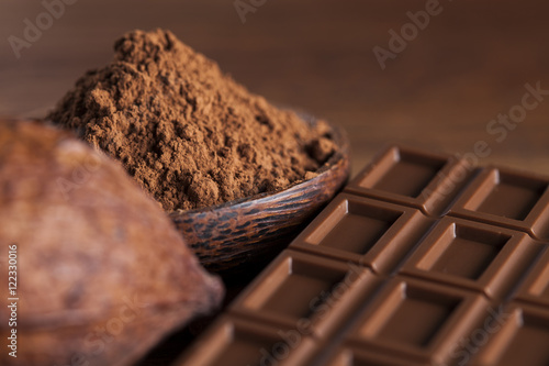 Chocolate bar, candy sweet, cacao beans and powder on wooden bac