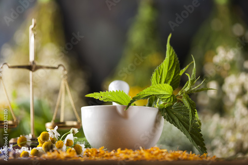 Herbs, berries and flowers with mortar, on wooden table backgrou
