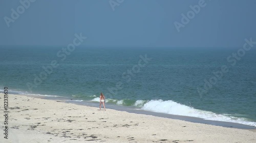 Bikini clad woman walking along Ho Hum beach on Fire Island photo