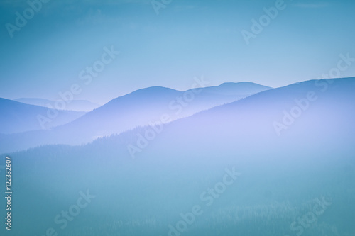 Landscape with colorful layers of mountains and haze in the valleys. The effect of color tinting.