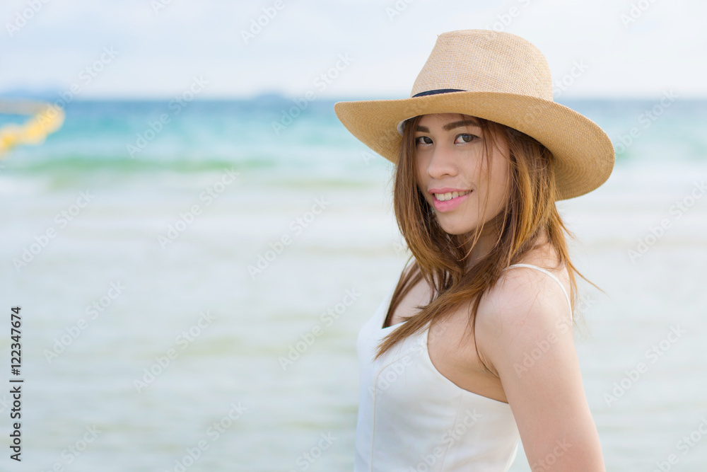 Young woman in long white dress and hat leying on white sand  at sunset on the sea. having great summer time on holidays. Summer vacation, holidays, serenity, travel.
