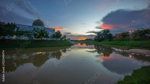 Majestic sunset sky over a mosque by the lake with perfect reflection. Time lapse.  photo