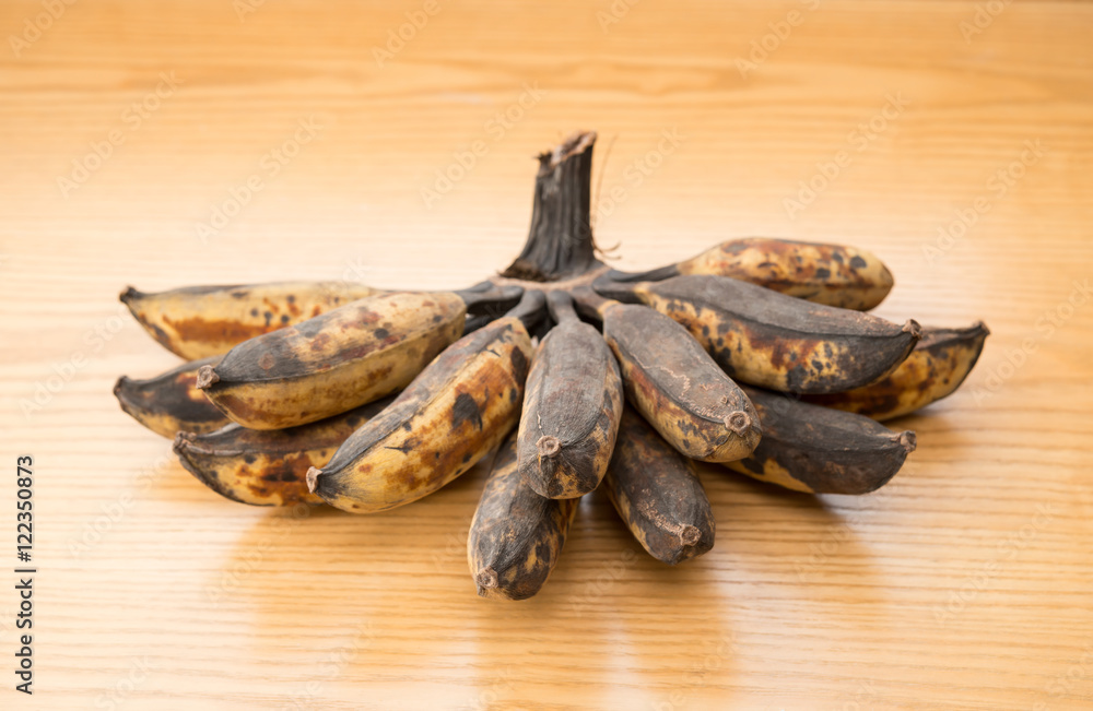 bunch of black overripe bananas on a wooden background bunch of black overripe bananas on a wooden background