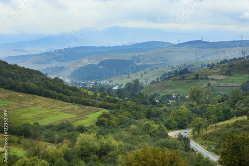 Aerial view on mountain pass landscape with green forest and a road