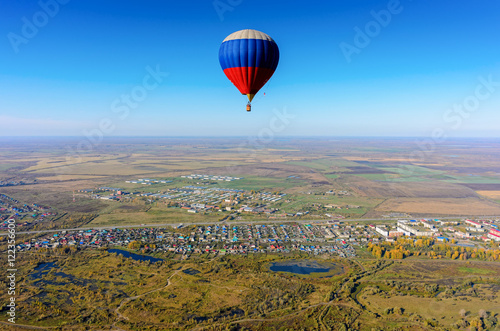 Hot air balloon flying over rural landscape at autumn day. Kaskara. Tyumen region. Russia