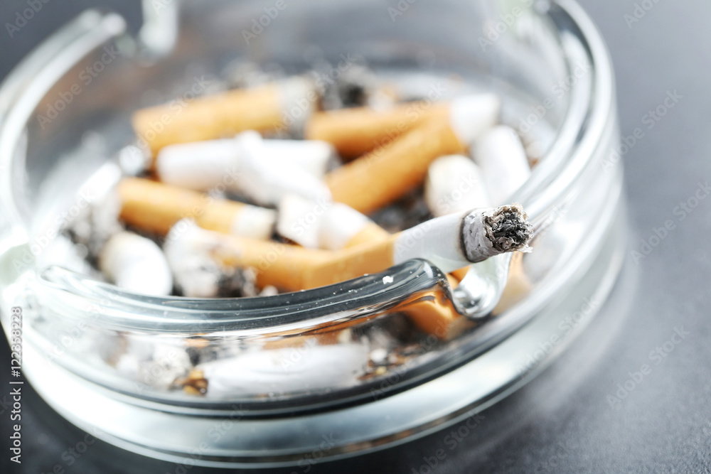 Cigarette butts with ash in ashtray on black background Cigarette butts with ash in ashtray on black background