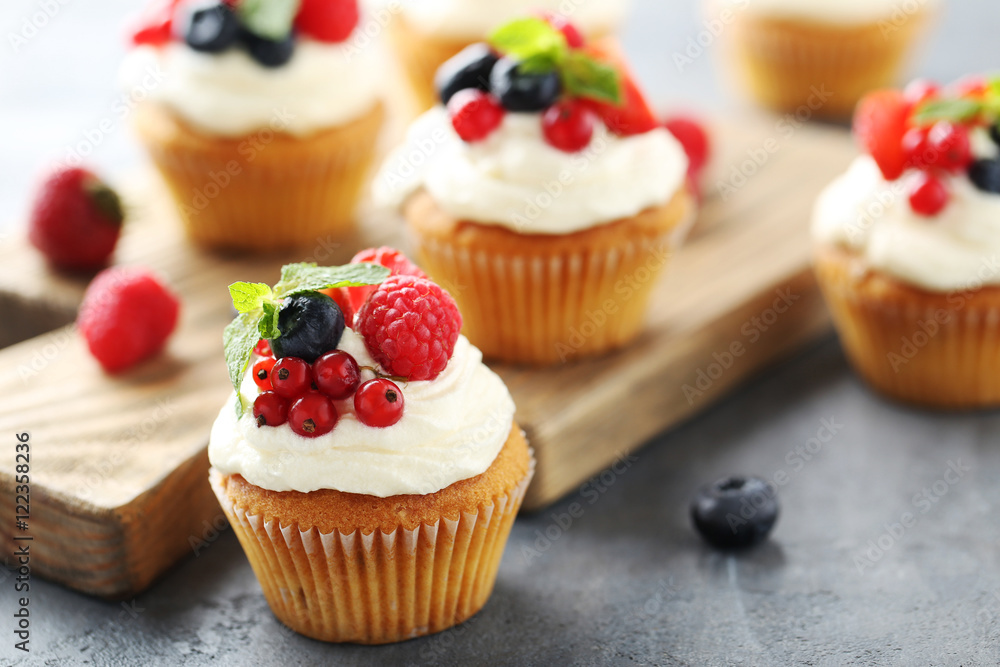 Tasty cupcakes with berries on cutting board