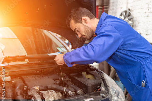 Young attractive mechanic working on a car at the garage photo