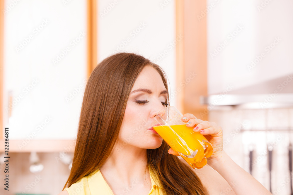 Woman in kitchen drinking fresh orange juice Woman in kitchen drinking fresh orange juice
