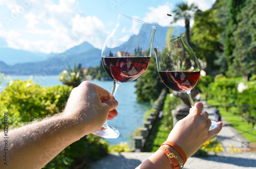 Wineglasses in the hands against lake Como, Italy